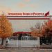 Front view of International School of Prishtina with autumn trees and flags.
